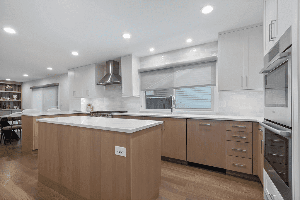 A kitchen with wooden cabinets , white counter tops , and stainless steel appliances.