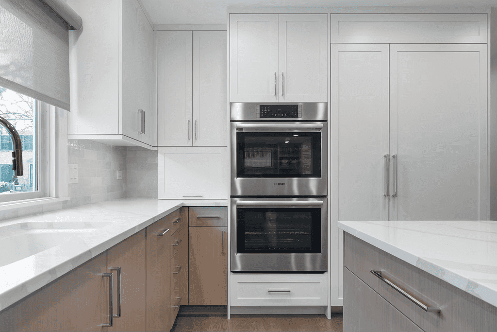 A kitchen with white cabinets , stainless steel appliances , a sink , and a window.