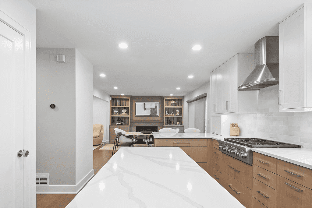 A kitchen with a large island in the middle and a living room in the background.