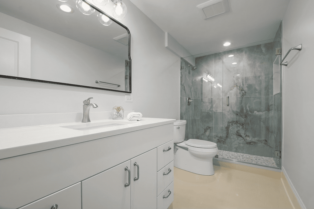 A bathroom with a sink , toilet , shower and mirror.