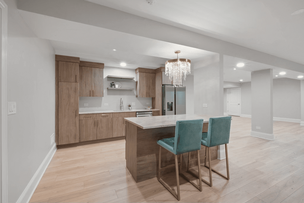 A kitchen in a basement with a table and chairs.