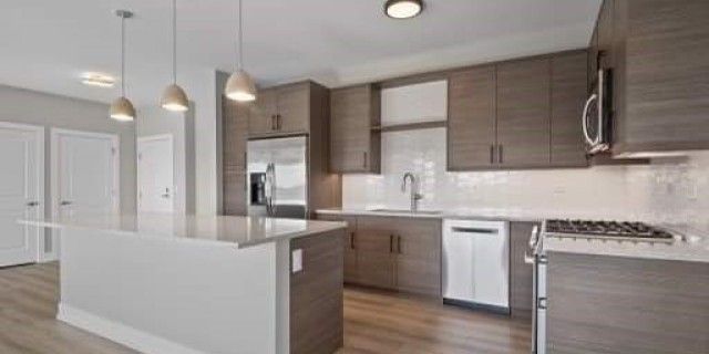 A kitchen with wooden cabinets , a stove , a refrigerator , a microwave , and a sink.
