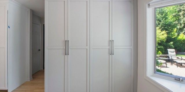 A room with white cabinets and a window with a view of a garden.