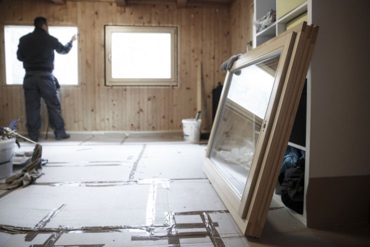 A man is installing a window in a room with wooden walls.
