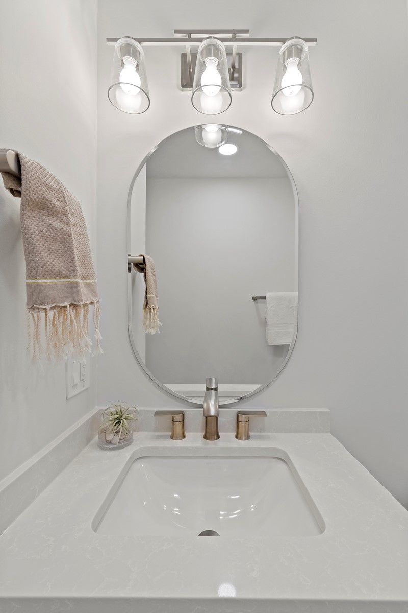 A bathroom with a sink , mirror and light fixture.
