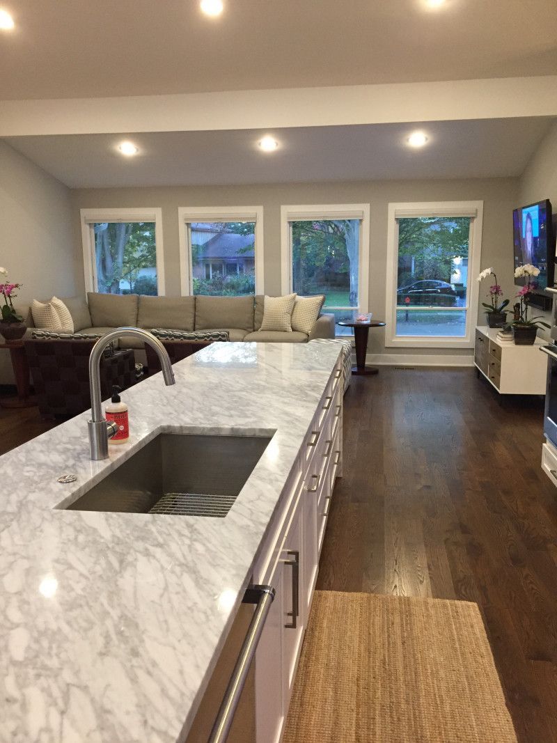 A kitchen with a marble counter top and a stainless steel sink.