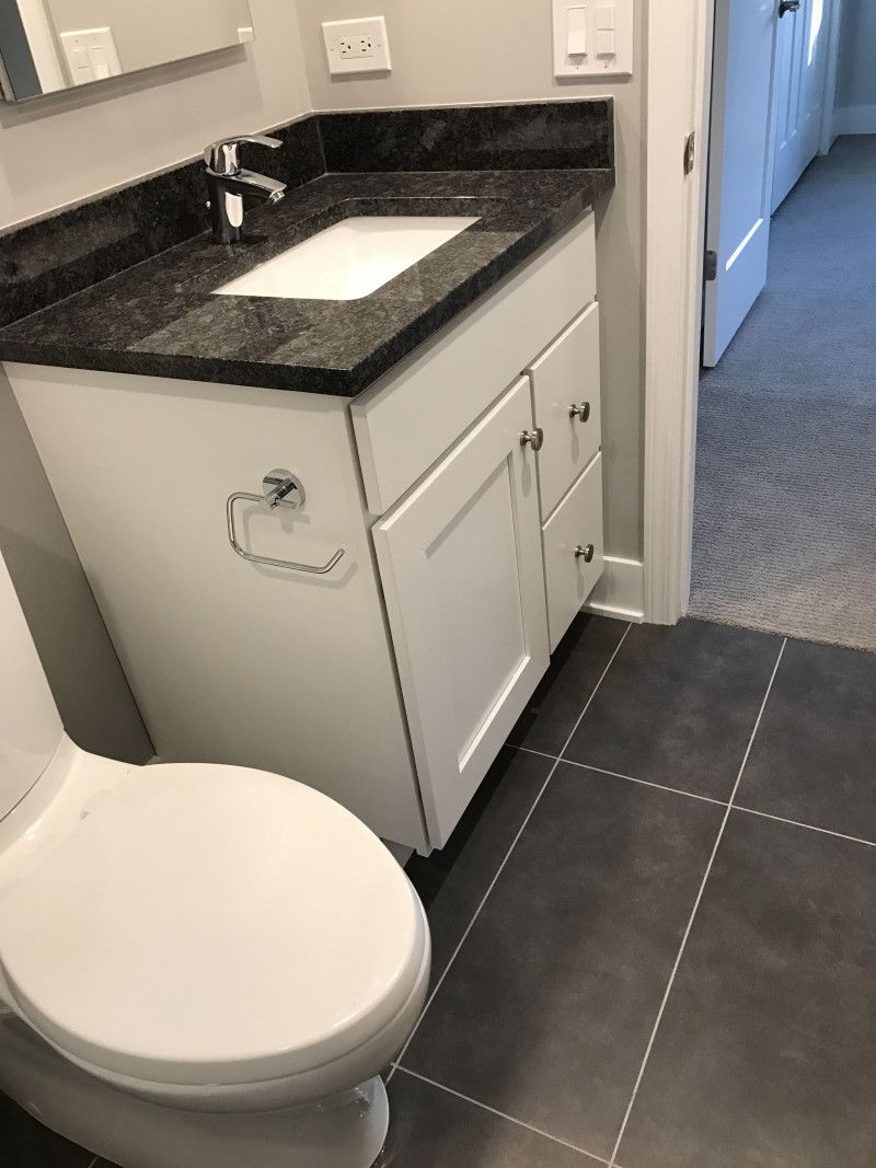 A bathroom with a toilet , sink and mirror.