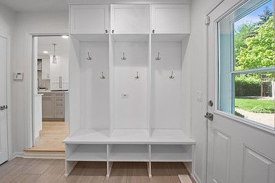 A white mud room with a bench and hooks.