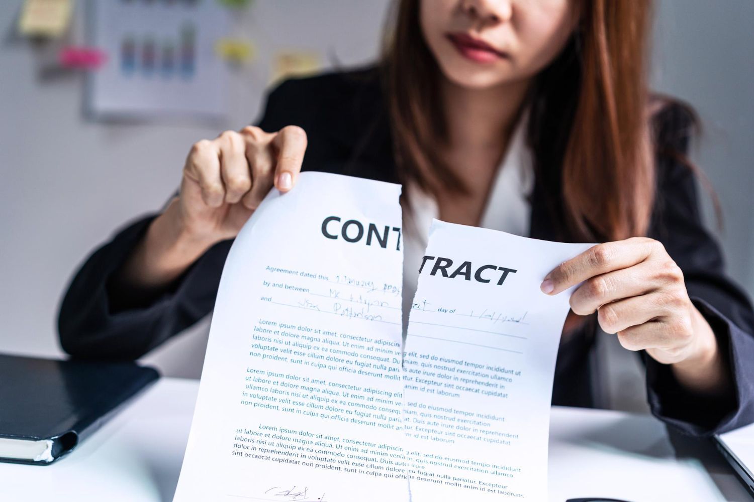 Woman tearing a contract document at a desk