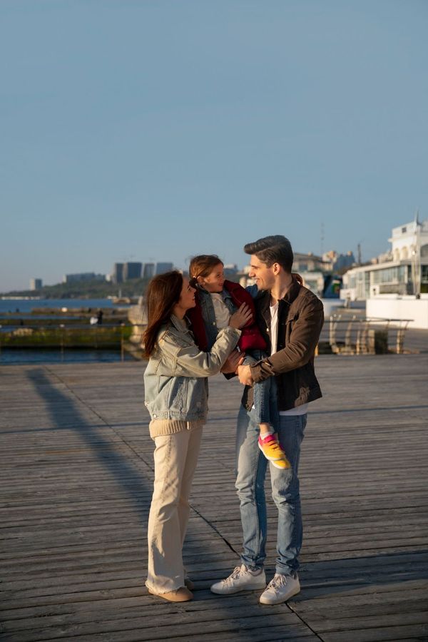 Couple standing on a boardwalk at sunset, holding hands and chatting by the water.