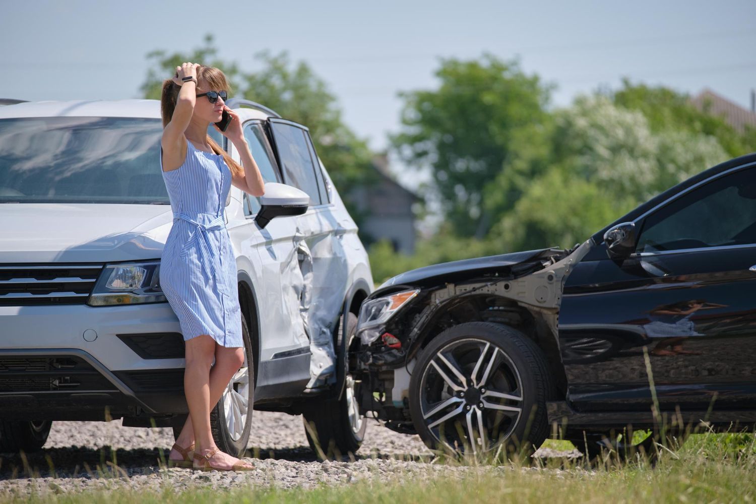 Woman on roadside near two damaged cars after a collision.