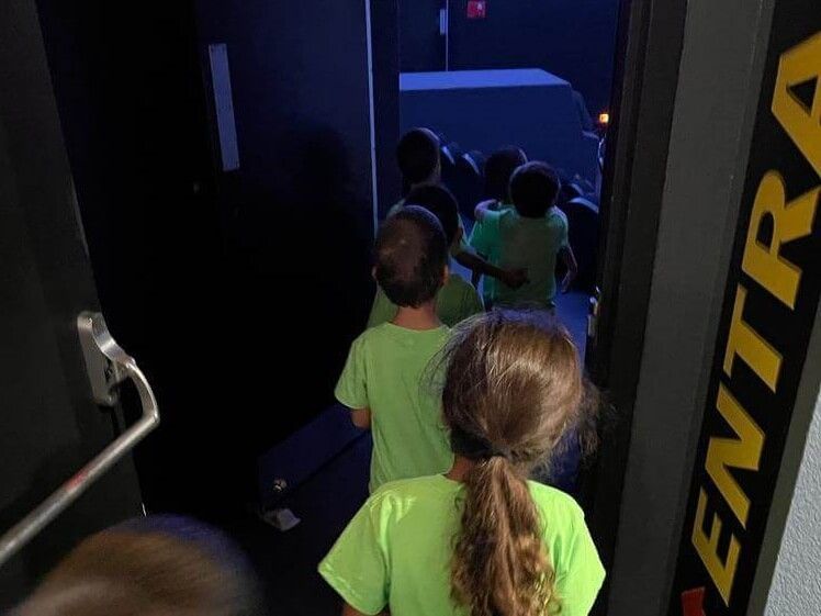 A group of children are walking through a doorway that says entrada