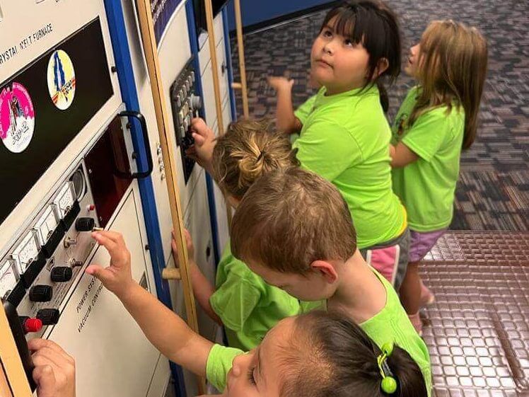 A group of children in green shirts are playing with a machine.