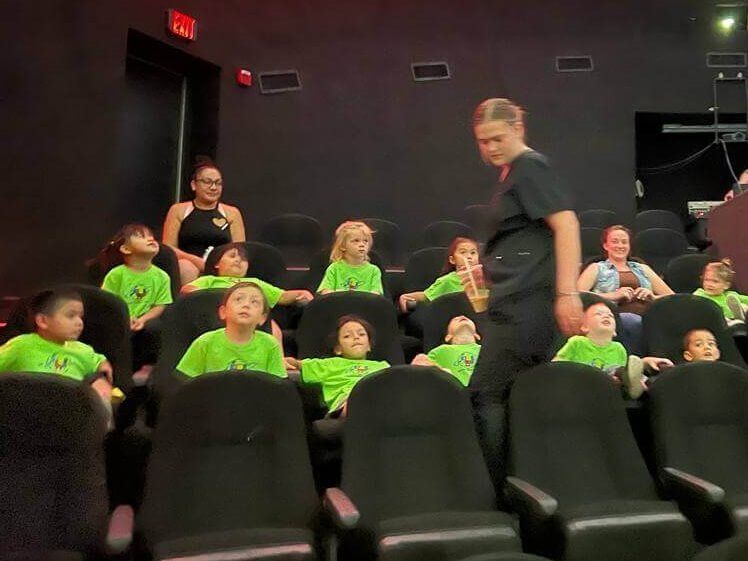 A group of children are sitting in a theater watching a movie.