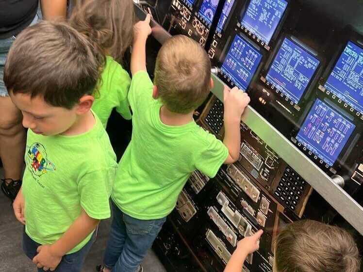 A group of young children are looking at a computer screen.