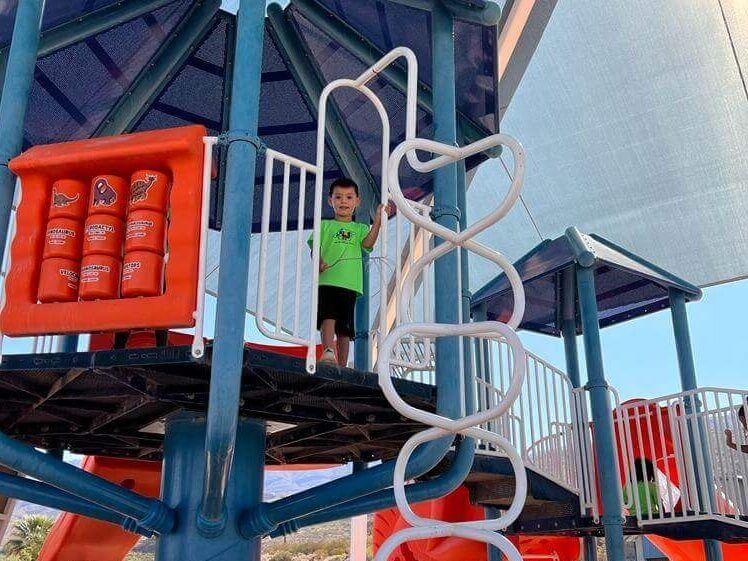 A young boy is standing on top of a playground structure.