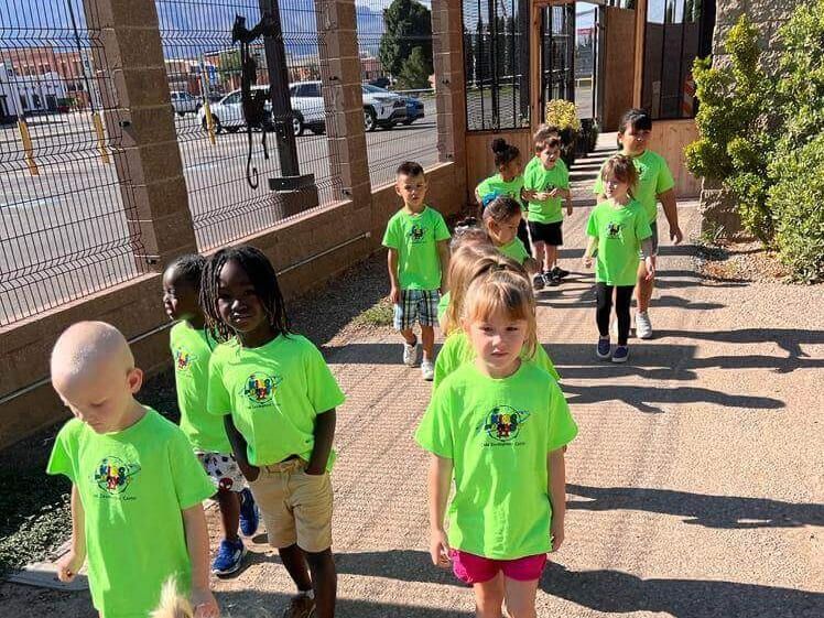 A group of children wearing neon green shirts are walking down a sidewalk.