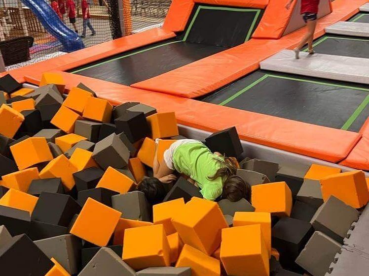A girl is laying in a pile of foam cubes on a trampoline.