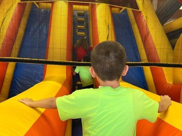 A young boy in a green shirt is playing in a bouncy house