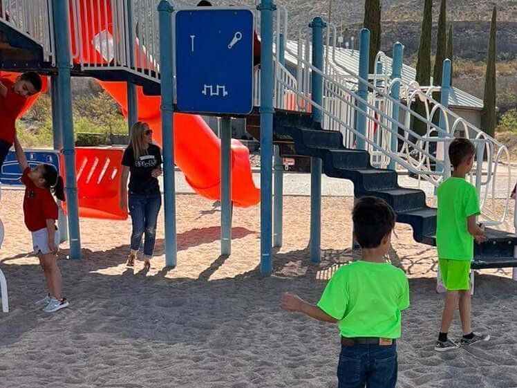 A group of children are playing in a playground with a sign that says 