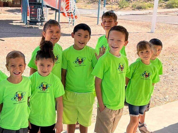 A group of children wearing neon green shirts are posing for a picture.