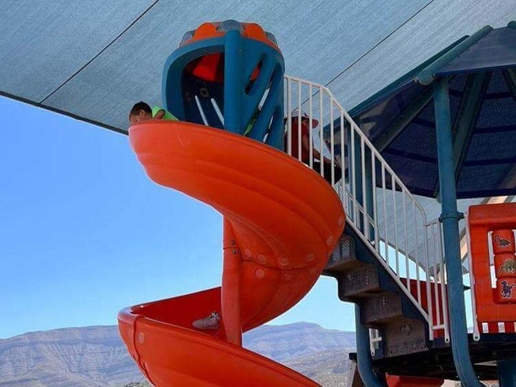 A child is playing on a spiral slide at a playground