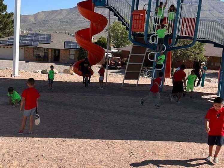 A group of children are playing in a playground with an orange slide