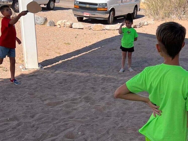 A boy in a green shirt is standing in the sand