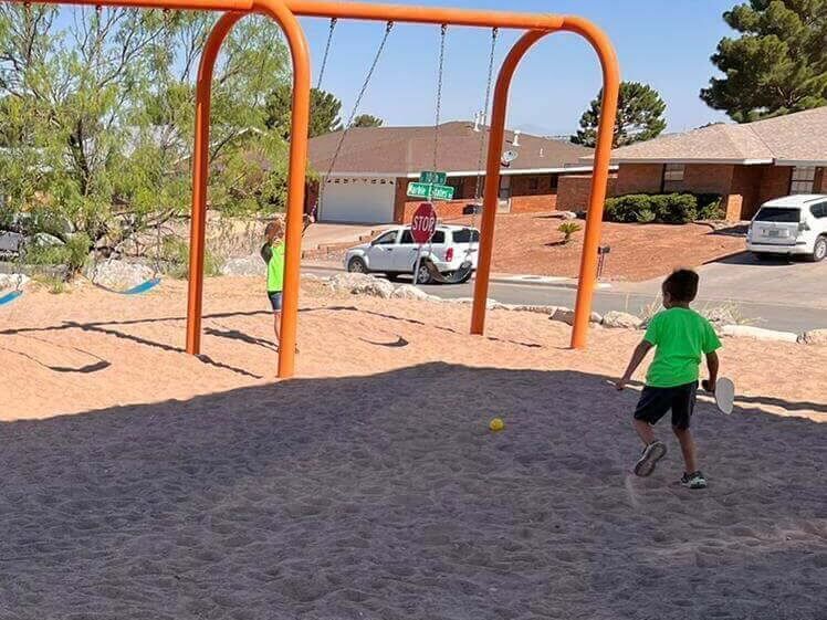 A boy in a green shirt is swinging on a swing set