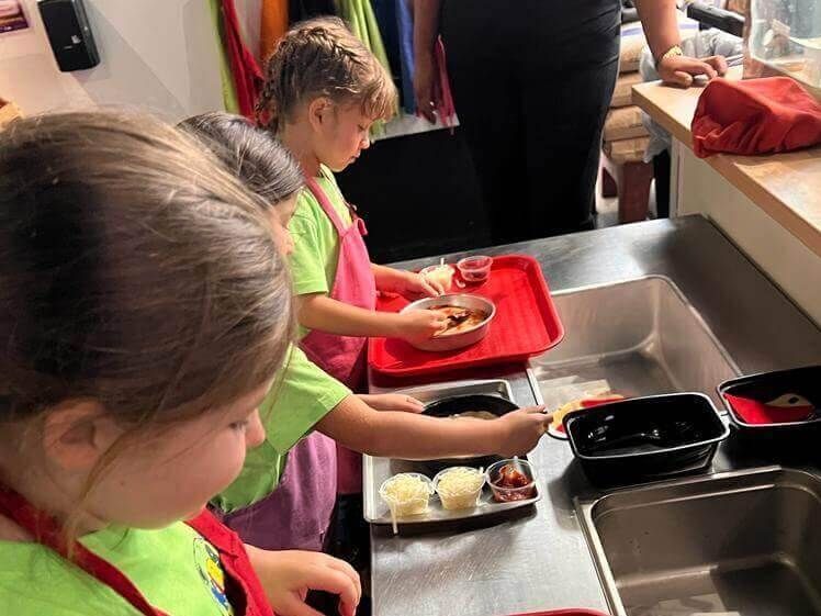 A group of young girls are preparing food in a kitchen.