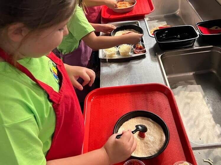 A group of children are preparing food in a kitchen.