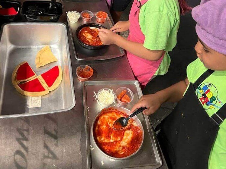 A group of children are making pizzas in a kitchen.