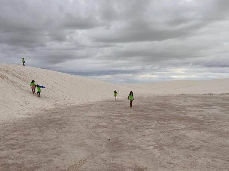 A group of people are walking up a sand dune.