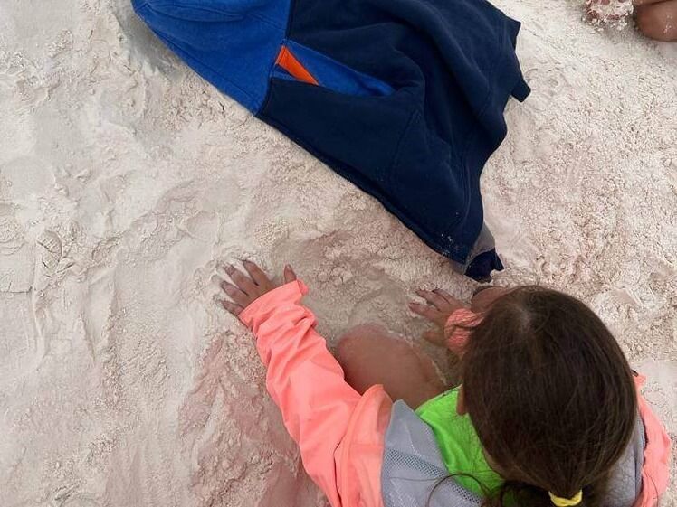A little girl is playing in the sand on the beach.