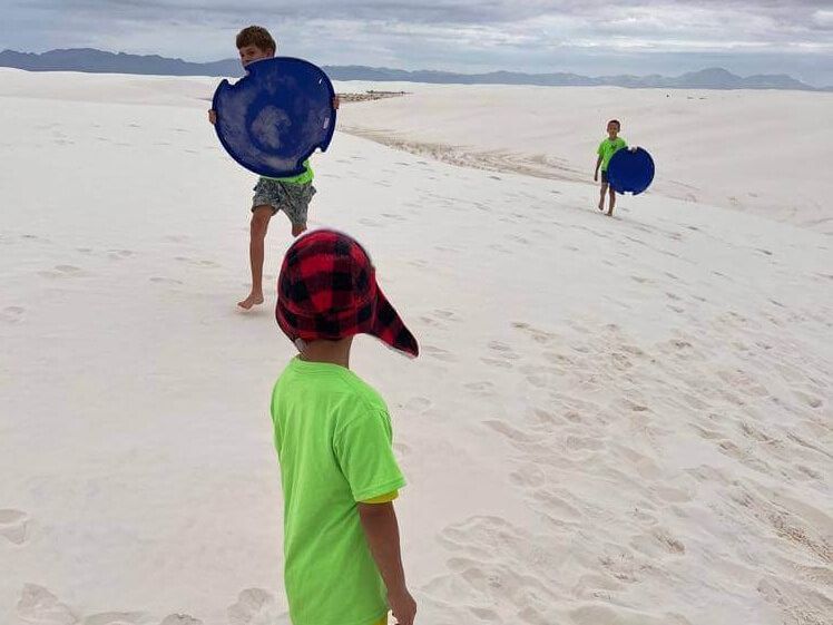 A group of children are playing frisbee on a sandy beach.