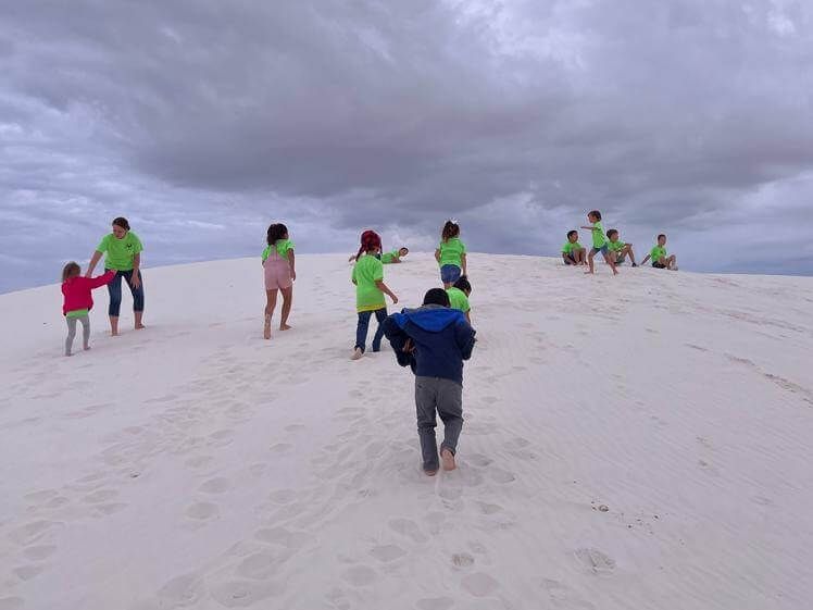 A group of people are standing on top of a sand dune.
