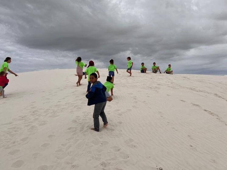 A group of people standing on top of a sand dune