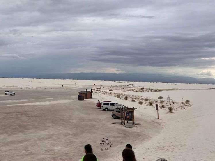 A group of people are standing on a sandy beach.