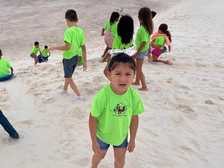 A group of children are playing in the sand on a beach.