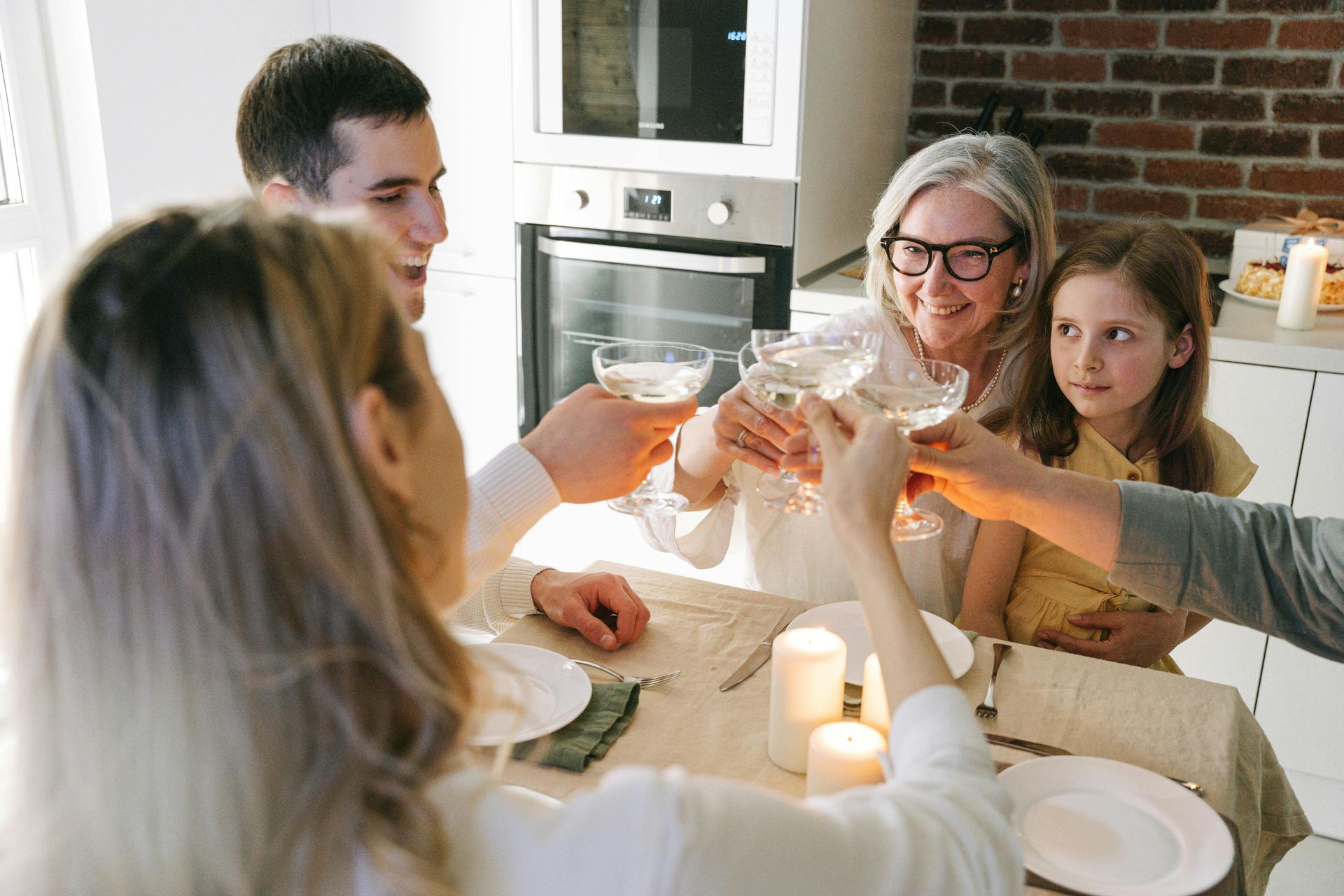A woman in a pink shirt is standing in front of a family sitting at a table.