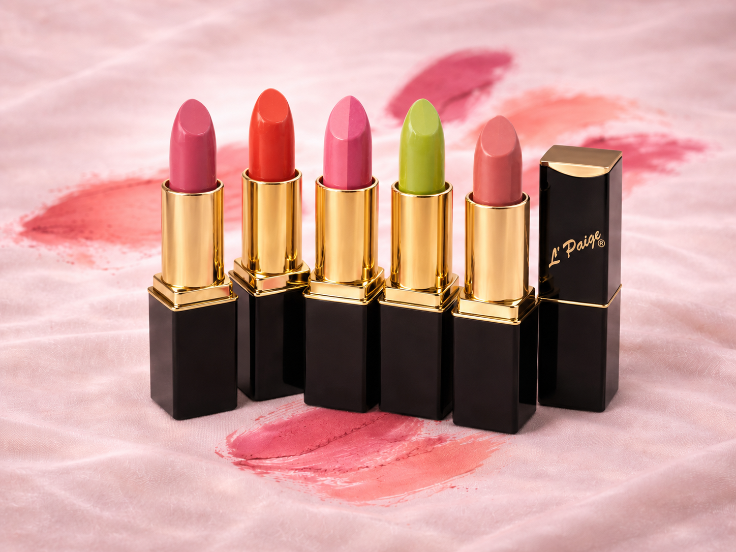 A model wearing pink lip gloss beside an open tube of lip gloss against a soft-focus, glittery, light-pink background.