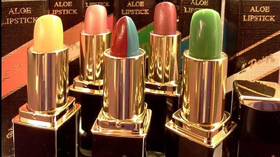 Colorful ALOB lipsticks in gold cases, displayed in a row against branded boxes.