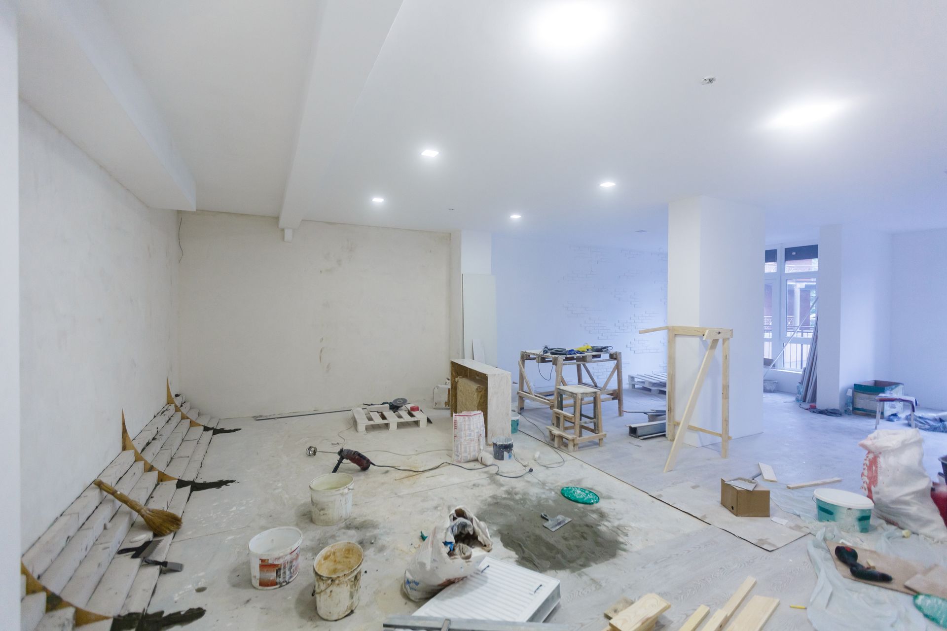 Interior of a room under renovation, with tools and materials scattered across the floor.