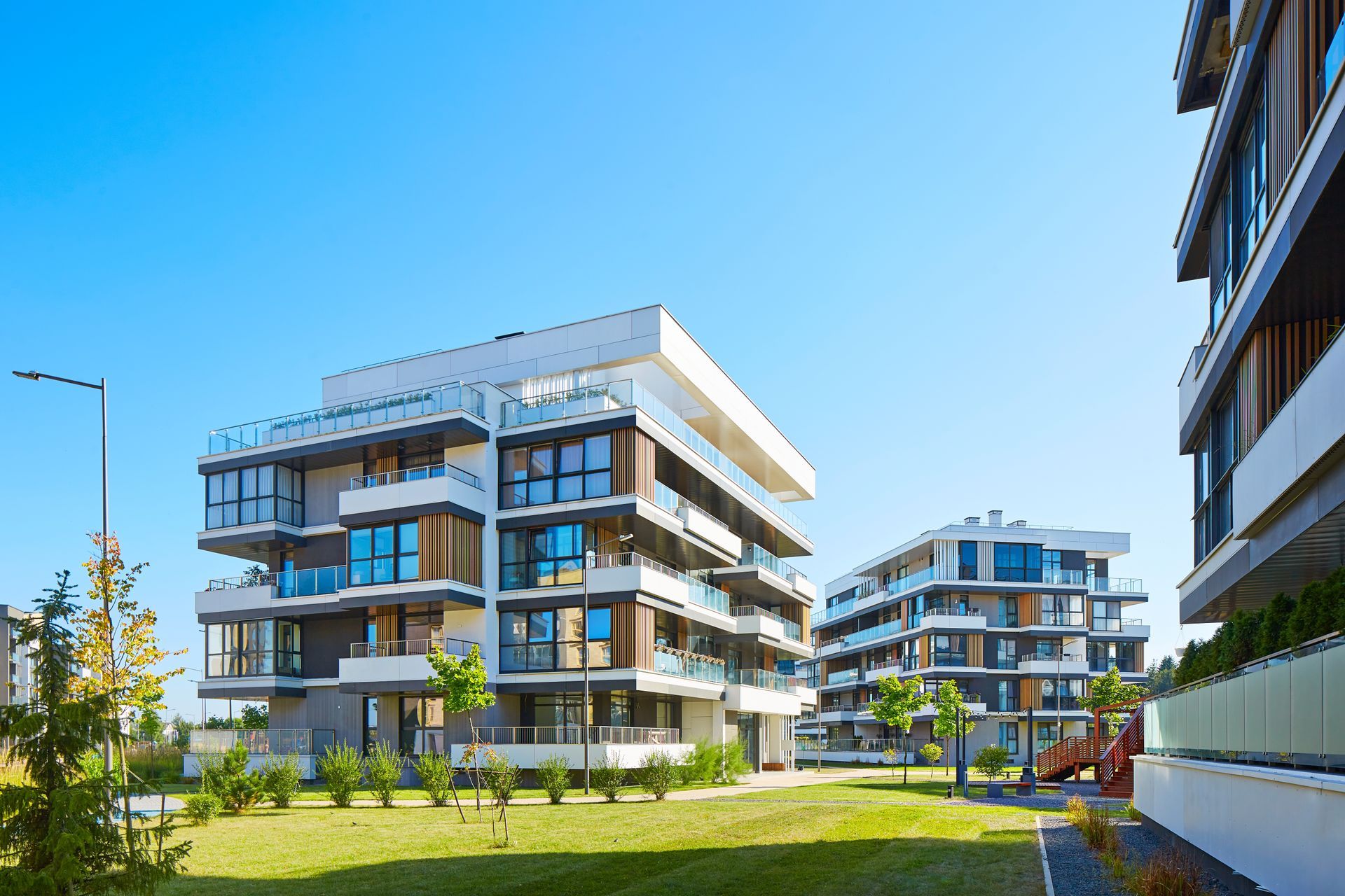Modern apartment buildings with glass balconies, sunny day.
