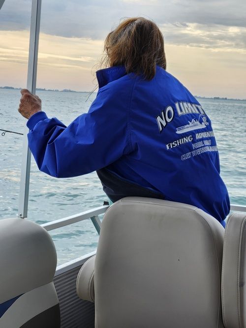 Person on a boat, fishing, wearing a blue jacket with 