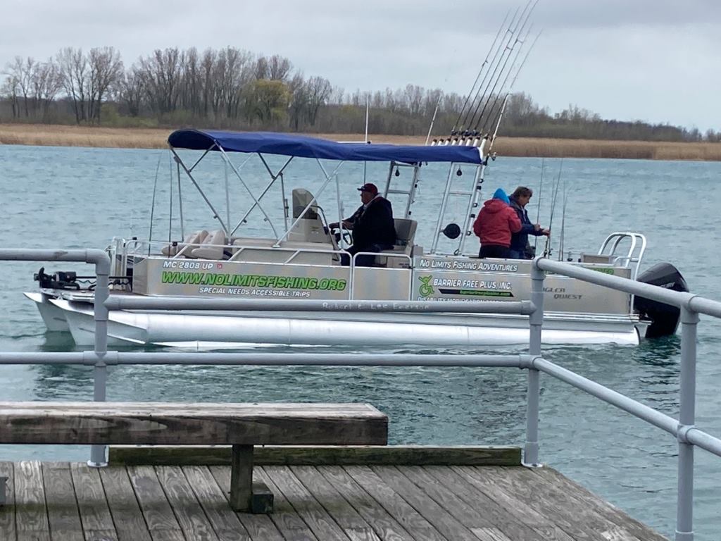Pontoon boat with people fishing, on the water; overcast day.