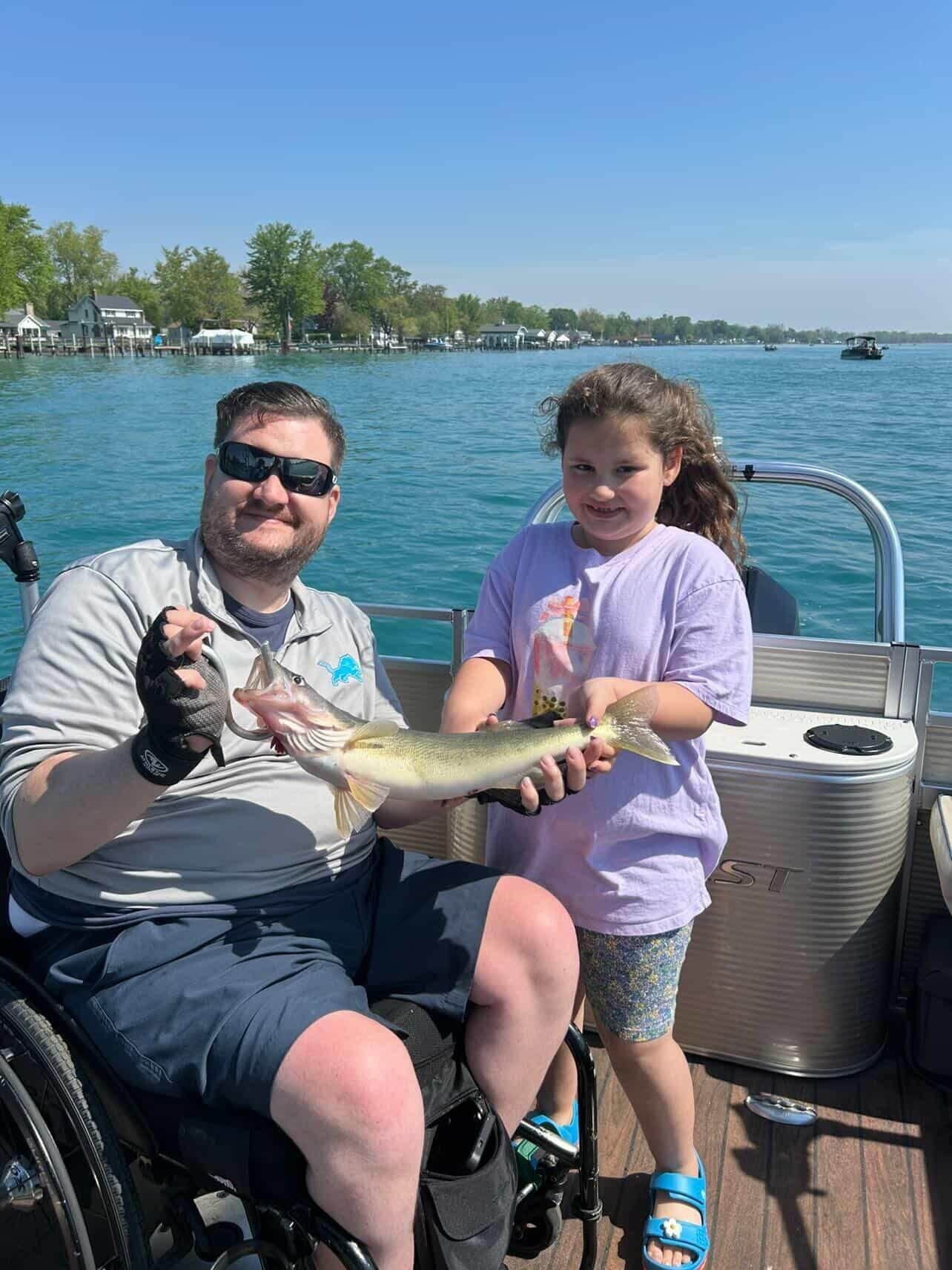 Man and child on a boat holding up a fish on a sunny lake