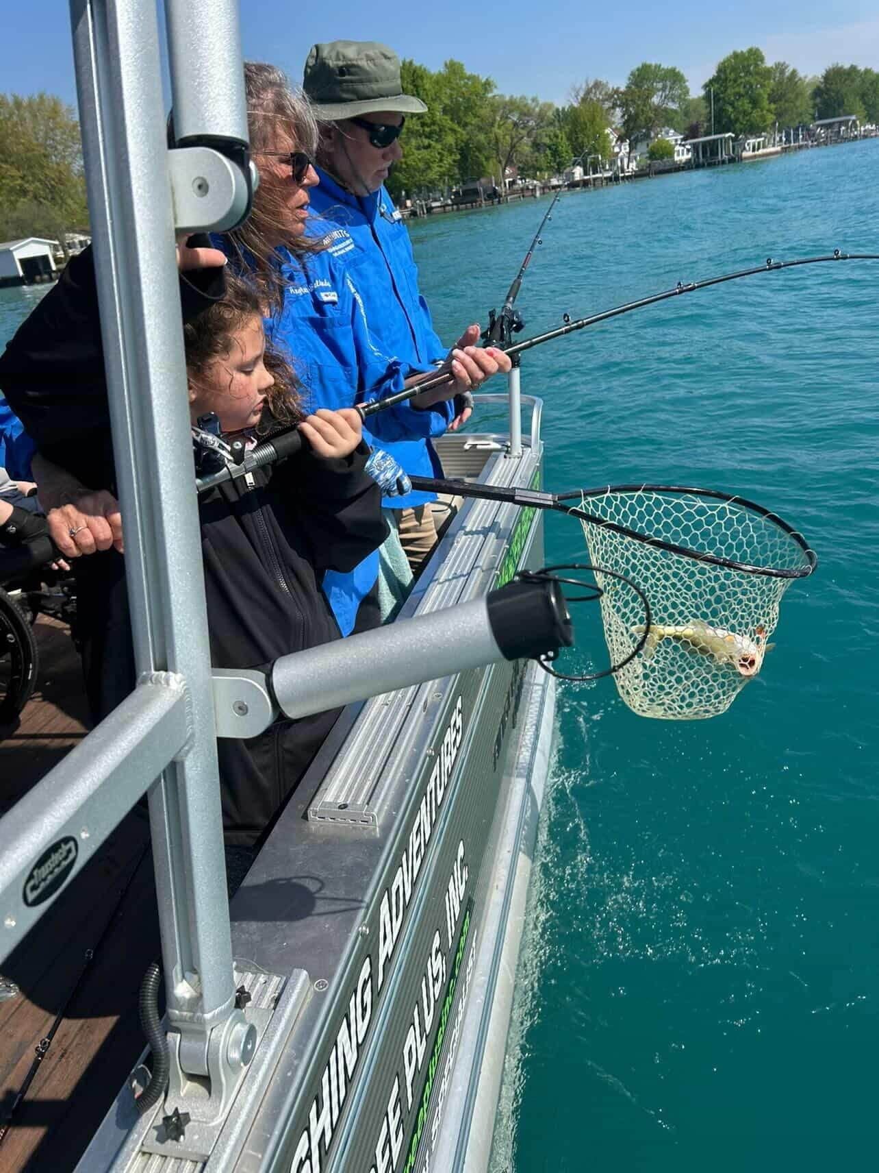 People on a boat fishing with a net over bright blue water