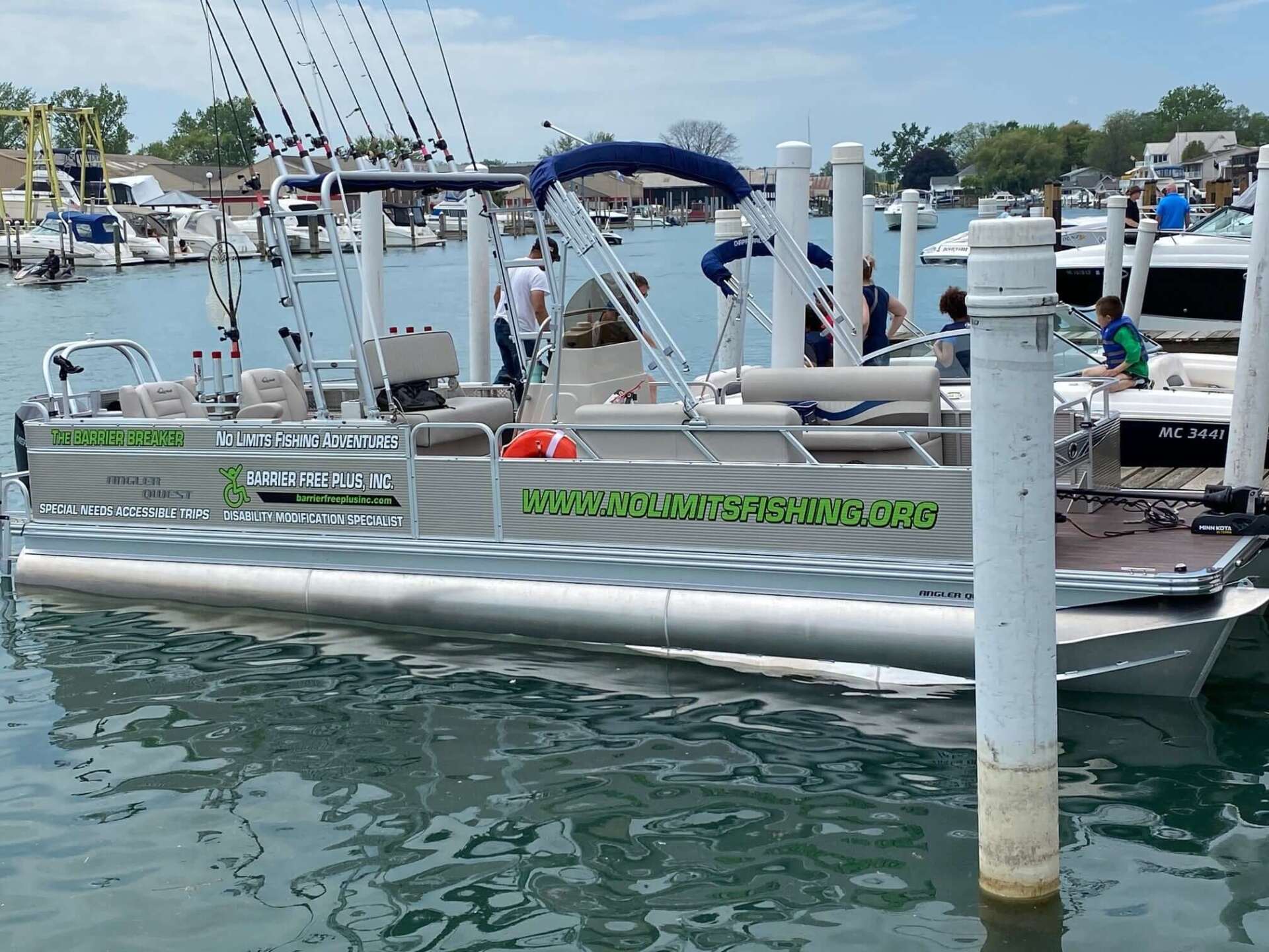 Pontoon boat at a dock; it has fishing rods and signage,
