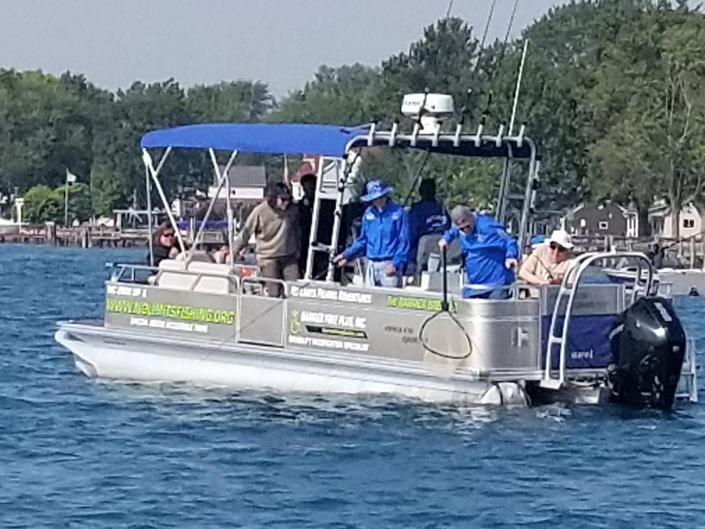A pontoon boat on water with people fishing.